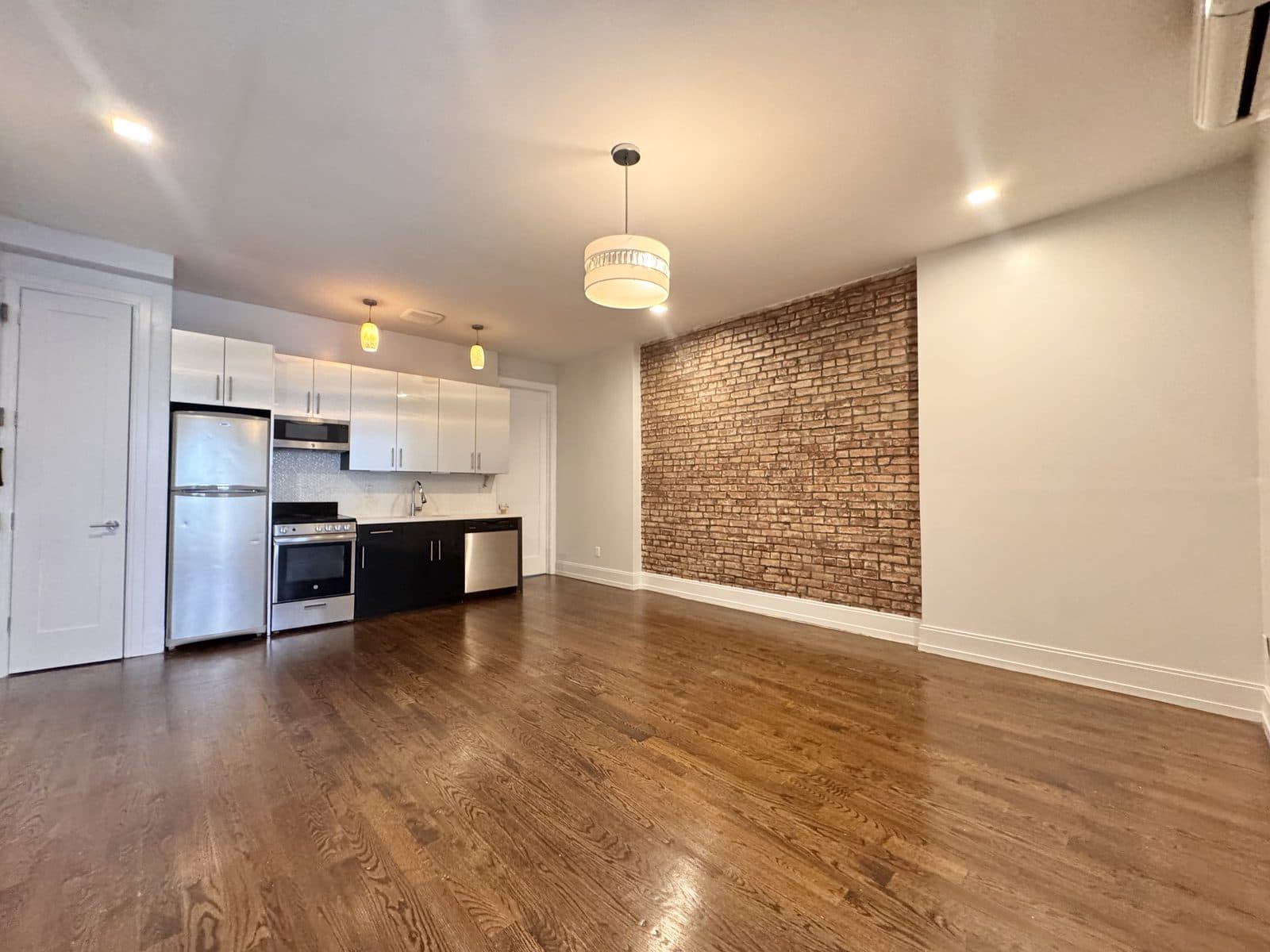 Open kitchen with white cabinets beside an exposed brick wall