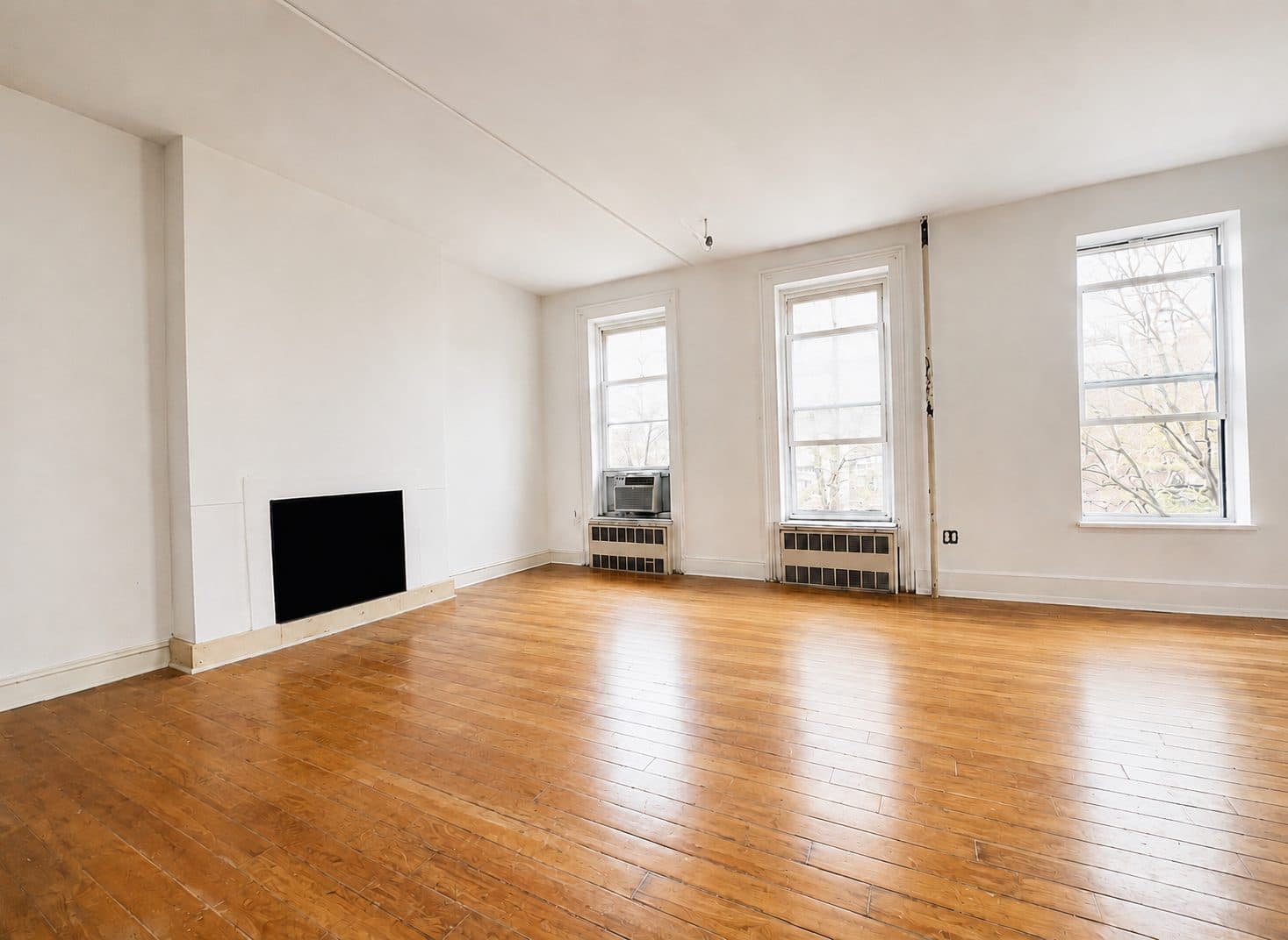 Empty prewar living room with three tall windows
