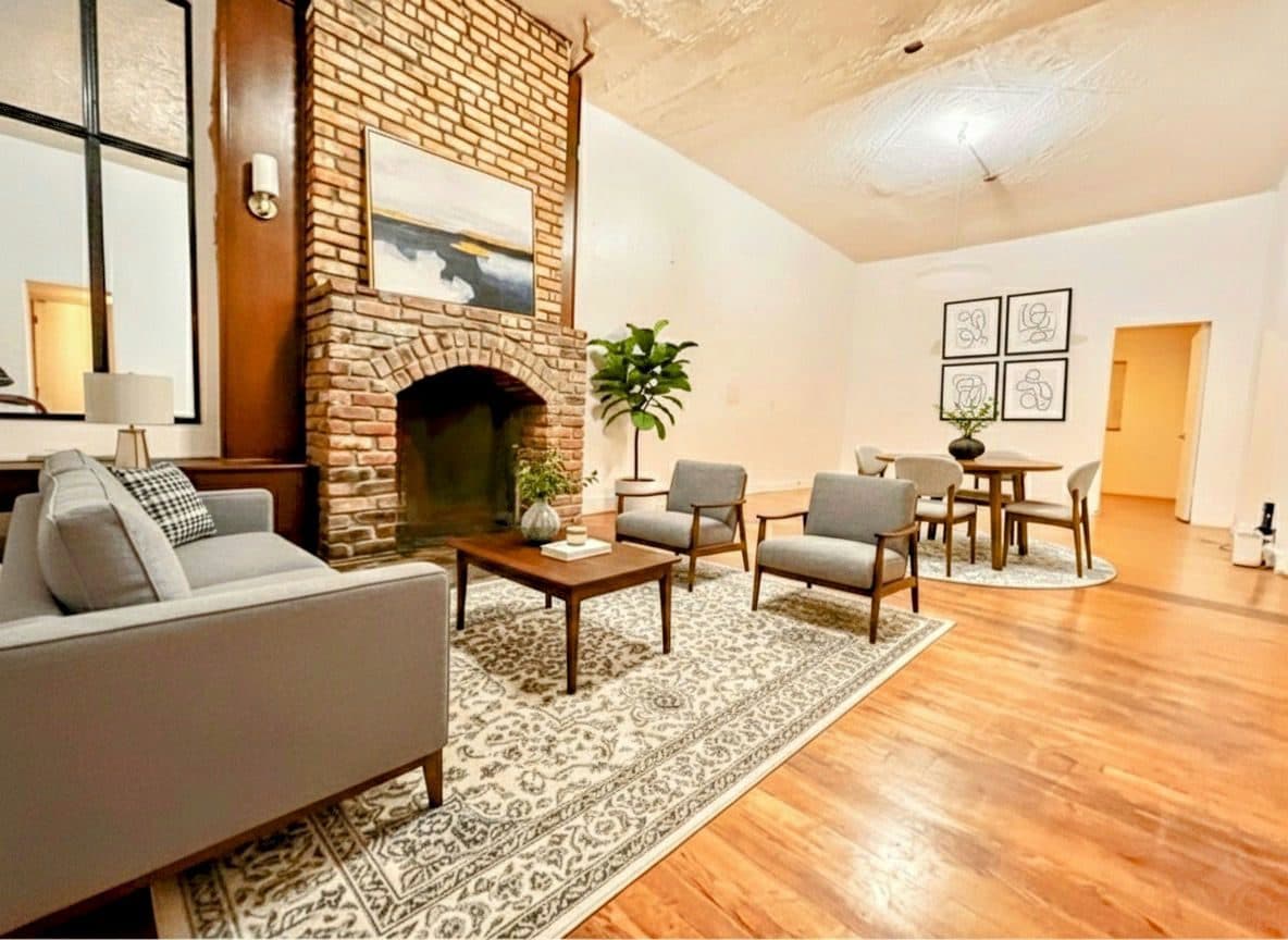 Living room with an exposed brick fireplace, virtually staged
