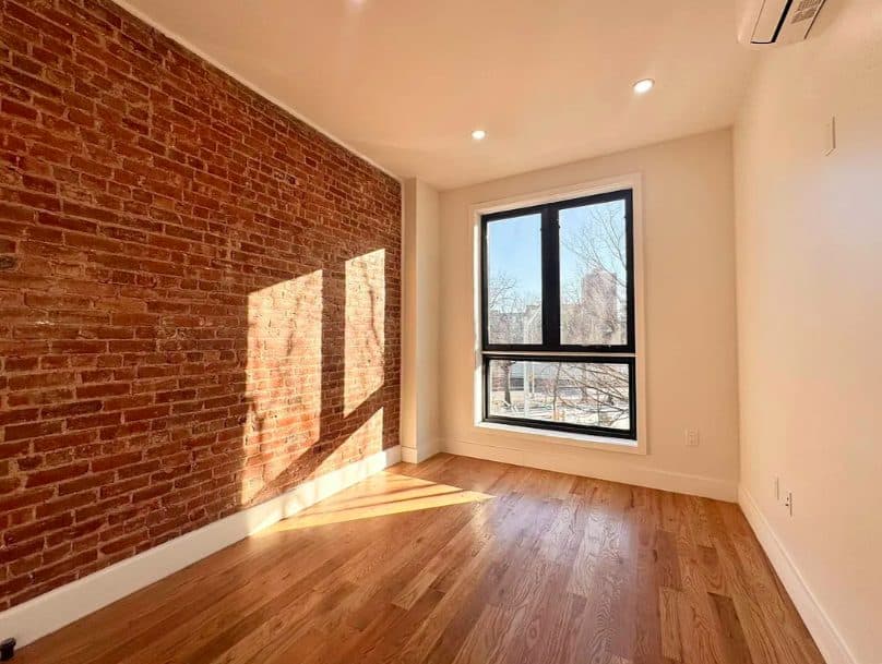 Empty room with an exposed brick wall and large windows